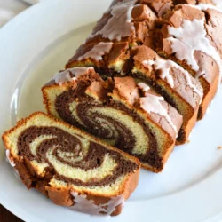 Für den Mocha Swirl Pound Cake brauchst du folgende Hauptzutaten: - 1 Tasse ungesalzene Butter, weich - 1 ½ Tassen Kristallzucker - 4 große Eier - 2 Tassen Weizenmehl - 1 Teelöffel Backpulver - ½ Teelöffel Salz - ½ Tasse frisch gebrühter Kaffee, abgekühlt - ½ Tasse ungesüßtes Kakaopulver - 1 Teelöffel Vanilleextrakt - 1 Teelöffel Espressopulver Diese Zutaten machen den Kuchen saftig und voller Geschmack. Die Butter sorgt für die richtige Textur. Zucker und Eier geben dem Kuchen die nötige Süße und Feuchtigkeit. Für den Guss benötigst du: - 1 Tasse Puderzucker - 2 Esslöffel Milch Der Guss verleiht dem Kuchen eine süße Note. Er rundet den Geschmack perfekt ab und sorgt für ein schönes Finish. Du benötigst einige Werkzeuge, um den Kuchen zuzubereiten: - Eine 9x5-Zoll Kastenform - Eine große Schüssel - Einen Handmixer oder eine Küchenmaschine - Ein Messer zum Marmorieren - Eine kleine Schüssel für den Guss Diese Werkzeuge helfen dir, den Kuchen einfach und schnell zu backen. Die Kastenform sorgt dafür, dass der Kuchen gleichmäßig backt. {{ingredient_image_2}} Zuerst heizen Sie Ihren Ofen auf 175°C vor. Nehmen Sie eine Kastenform von 9x5 Zoll und fetten Sie sie gut ein. Das hilft dem Kuchen, nicht zu kleben. Stellen Sie sicher, dass alle Zutaten bei Raumtemperatur sind. So vermischen sie sich besser und der Teig wird gleichmäßiger. In einer großen Schüssel schlagen Sie 1 Tasse weiche Butter und 1 ½ Tassen Kristallzucker mit einem Handmixer. Rühren Sie, bis die Mischung hell und luftig ist. Fügen Sie dann 4 große Eier nacheinander hinzu. Rühren Sie gut um, damit alles gut vermischt ist. In einer anderen Schüssel mischen Sie 2 Tassen Weizenmehl, 1 Teelöffel Backpulver und ½ Teelöffel Salz. Geben Sie diese Mischung langsam zur Buttermischung. Fügen Sie dabei ½ Tasse abgekühlten Kaffee hinzu. Rühren Sie nur, bis alles gut vermischt ist. Teilen Sie den Teig in zwei Hälften. In einer Hälfte rühren Sie ½ Tasse ungesüßtes Kakaopulver, 1 Teelöffel Espressopulver und 1 Teelöffel Vanilleextrakt ein. Jetzt haben Sie einen hellen und einen dunklen Teig. Um die Marmorierung zu machen, löffeln Sie abwechselnd die beiden Teige in die Form. Beginnen Sie mit dem Vanilleteig, gefolgt vom Schokoladenteig. Wiederholen Sie das, bis beide Teige aufgebraucht sind. Nehmen Sie ein Messer und ziehen Sie es vorsichtig durch die Teige. Das ergibt einen schönen Marmoreffekt. Backen Sie den Kuchen für 50-60 Minuten. Prüfen Sie mit einem Zahnstocher, ob der Kuchen fertig ist. Lassen Sie den Kuchen 10 Minuten in der Form abkühlen. Dann legen Sie ihn auf ein Kuchengitter, damit er ganz abkühlt. Um die beste Textur in Ihrem Mocha Swirl Pound Cake zu haben, verwenden Sie weiche Butter. Das macht den Teig luftig. Mischen Sie die Zutaten nicht zu lange. So bleibt der Kuchen saftig. Ein guter Trick ist, den Kaffee abkühlen zu lassen. Warmer Kaffee kann den Teig schwer machen. Vergessen Sie nicht das Espressopulver. Es verstärkt den Kaffeegeschmack und gibt einen tollen Kick. Ein häufiger Fehler ist, die Eier zu schnell hinzuzufügen. Fügen Sie jedes Ei einzeln hinzu und rühren Sie gut. Ein weiterer Fehler ist, das Mehl zu schnell einzumischen. Gehen Sie langsam vor und mischen Sie nur bis alles vermischt ist. Dies verhindert, dass der Kuchen zäh wird. Achten Sie auch darauf, die Form gut zu fetten. Ein klebender Kuchen macht das Servieren schwierig. Für die beste Präsentation schneiden Sie den Kuchen in gleichmäßige Scheiben. Legen Sie die Scheiben auf eine schöne Servierplatte. Träufeln Sie etwas von dem Kaffeeguss obenauf. Es sieht nicht nur gut aus, sondern schmeckt auch besser. Servieren Sie den Kuchen mit frischem Kaffee. Diese Kombination ist ein echter Genuss. Pro Tipps Die richtige Buttertemperatur: Stellen Sie sicher, dass die Butter weich ist, damit sie sich gut mit dem Zucker vermischen lässt und eine luftige Textur entsteht. Kaffee abkühlen lassen: Lassen Sie den frisch gebrühten Kaffee auf Raumtemperatur abkühlen, bevor Sie ihn zum Teig hinzufügen, um die Konsistenz nicht zu beeinträchtigen. Marmoreffekt perfektionieren: Verwenden Sie ein Messer, um die beiden Teige vorsichtig zu vermischen, aber übertreiben Sie es nicht, um einen schönen Marmor-Effekt zu erzielen. Guss richtig anbringen: Träufeln Sie den Guss gleichmäßig über den Kuchen, während er noch leicht warm ist, damit er besser haftet und ein schöner Glanz entsteht. {{image_4}} Möchten Sie den Mocha Swirl Pound Cake verändern? Es gibt viele Optionen. Ersetzen Sie den Kaffee durch Tee. Matcha oder Chai geben einen tollen Geschmack. Für eine fruchtige Note fügen Sie etwas Zitronen- oder Orangenabrieb hinzu. Sie können auch Nüsse oder Schokoladenstückchen in den Teig mischen. Dies gibt Textur und Geschmack. Für glutenfreien Kuchen verwenden Sie eine Mischung aus glutenfreiem Mehl. Achten Sie darauf, eine gute Mischung zu wählen, die für Kuchen geeignet ist. Das Rezept bleibt gleich. Der Geschmack wird immer noch köstlich sein. Eine schöne Präsentation macht alles besser. Träufeln Sie etwas extra Guss über den Kuchen. Fügen Sie Schlagsahne oder frische Beeren hinzu. Diese machen den Kuchen noch attraktiver. Servieren Sie ihn mit einer Tasse frisch gebrühtem Kaffee. Die Aromen ergänzen sich perfekt. Um deinen Mocha Swirl Pound Cake frisch zu halten, lagere ihn in einem luftdichten Behälter. Du kannst ihn auch in Frischhaltefolie wickeln. Diese Methoden halten den Kuchen saftig und verhindern, dass er austrocknet. Stelle sicher, dass der Kuchen vollständig abgekühlt ist, bevor du ihn lagerst. So bleibt die Textur perfekt. Wenn du etwas Kuchen übrig hast, friere ihn ein. Schneide ihn in Scheiben, um die Portionen zu erleichtern. Wickel jede Scheibe in Frischhaltefolie und lege sie in einen Gefrierbeutel. So bleibt der Kuchen bis zu drei Monate frisch. Zum Auftauen lege die Scheiben einfach in den Kühlschrank oder lasse sie bei Raumtemperatur liegen. Der Mocha Swirl Pound Cake bleibt bei richtiger Lagerung etwa fünf bis sieben Tage frisch. Achte darauf, ihn an einem kühlen, trockenen Ort zu lagern. Wenn du ihn länger aufbewahren möchtest, ist das Einfrieren die beste Option. So kannst du jederzeit ein Stück genießen! Um den Mocha Swirl Pound Cake glutenfrei zu machen, benutze glutenfreies Mehl. Achte darauf, eine Mischung zu wählen, die für Kuchen geeignet ist. Dies hilft, die Textur und den Geschmack zu bewahren. Du kannst auch Mandelmehl oder Kokosmehl ausprobieren. Diese Mehle haben einen anderen Geschmack, also teste sie vorher. Ja, du kannst anstelle von Kaffee auch Milch oder pflanzliche Milch verwenden. Wenn du den Kaffeegeschmack nicht magst, probiere einen Schokoladeneisgetränk oder lösliches Kakaopulver. Du kannst auch eine Mischung aus Milch und Schokoladensirup verwenden. Dies gibt dem Kuchen eine süße Note. Der Mocha Swirl Pound Cake bleibt bei Raumtemperatur in einem luftdichten Behälter etwa fünf Tage frisch. Im Kühlschrank hält er sich bis zu einer Woche. Wenn du ihn einfrierst, bleibt er bis zu drei Monate gut. Achte darauf, ihn gut einzuwickeln, damit er keinen Frostgeschmack annimmt. Der Mocha Swirl Pound Cake ist ein einfacher Genuss. Wir haben seine Hauptzutaten und den Guss besprochen. Auch die nötigen Werkzeuge wurden genannt. Die Schritt-für-Schritt-Anleitung macht die Zubereitung leicht. Tipps zur perfekten Textur helfen, häufige Fehler zu vermeiden. Du kannst den Kuchen mit verschiedenen Aromen variieren und sogar glutenfrei machen. Achte beim Lagern auf die Frische. Dieser Kuchen ist vielseitig und hält lange. Nutze die FAQs für weitere Fragen. Jetzt bist du bereit, deinen eigenen Mocha Swirl Pound Cake zu backen!